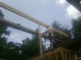Carpenter setting a ridge beam over a new addition frame — Ice Dam Removal by Roofing Brothers in Springvale