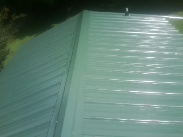 New green metal panels meeting at the ridge of a roof — Flat Roof Repair work by our crew in Springvale