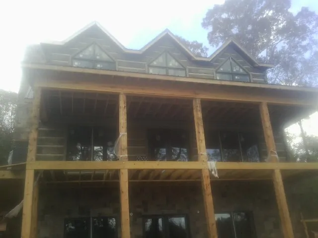 Dormers and porch framing on a large log home under construction — Roof Coating work by our crew in Springvale