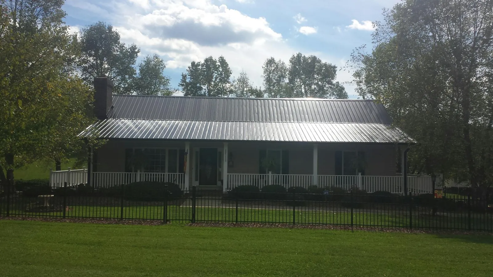 Gray metal roof on a brick ranch with a full width front porch — Gutter Guard Installation work by our crew in Springvale