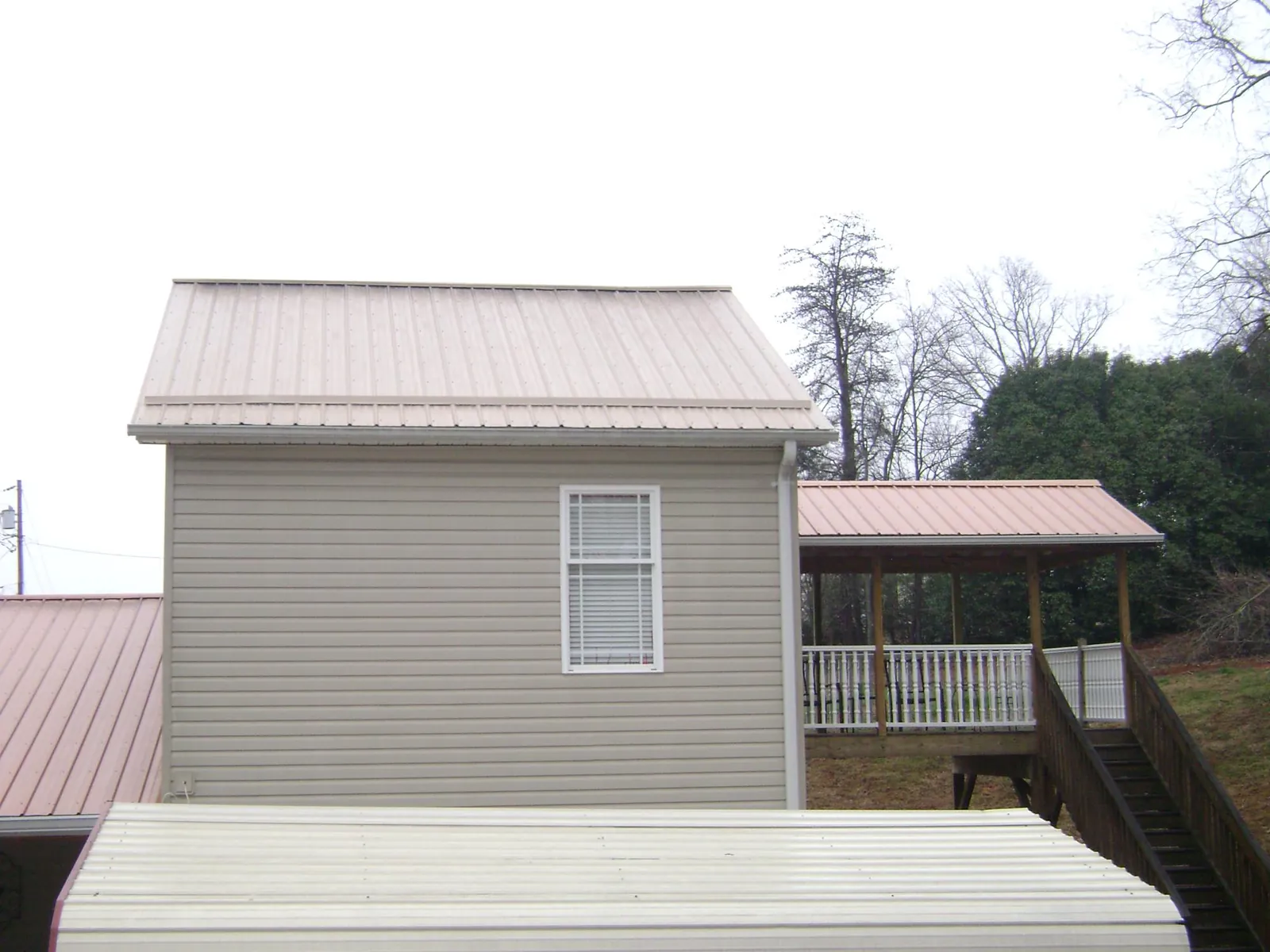 Tan metal roofs on a two story addition and attached porch, from a Roof Replacement job in Springvale