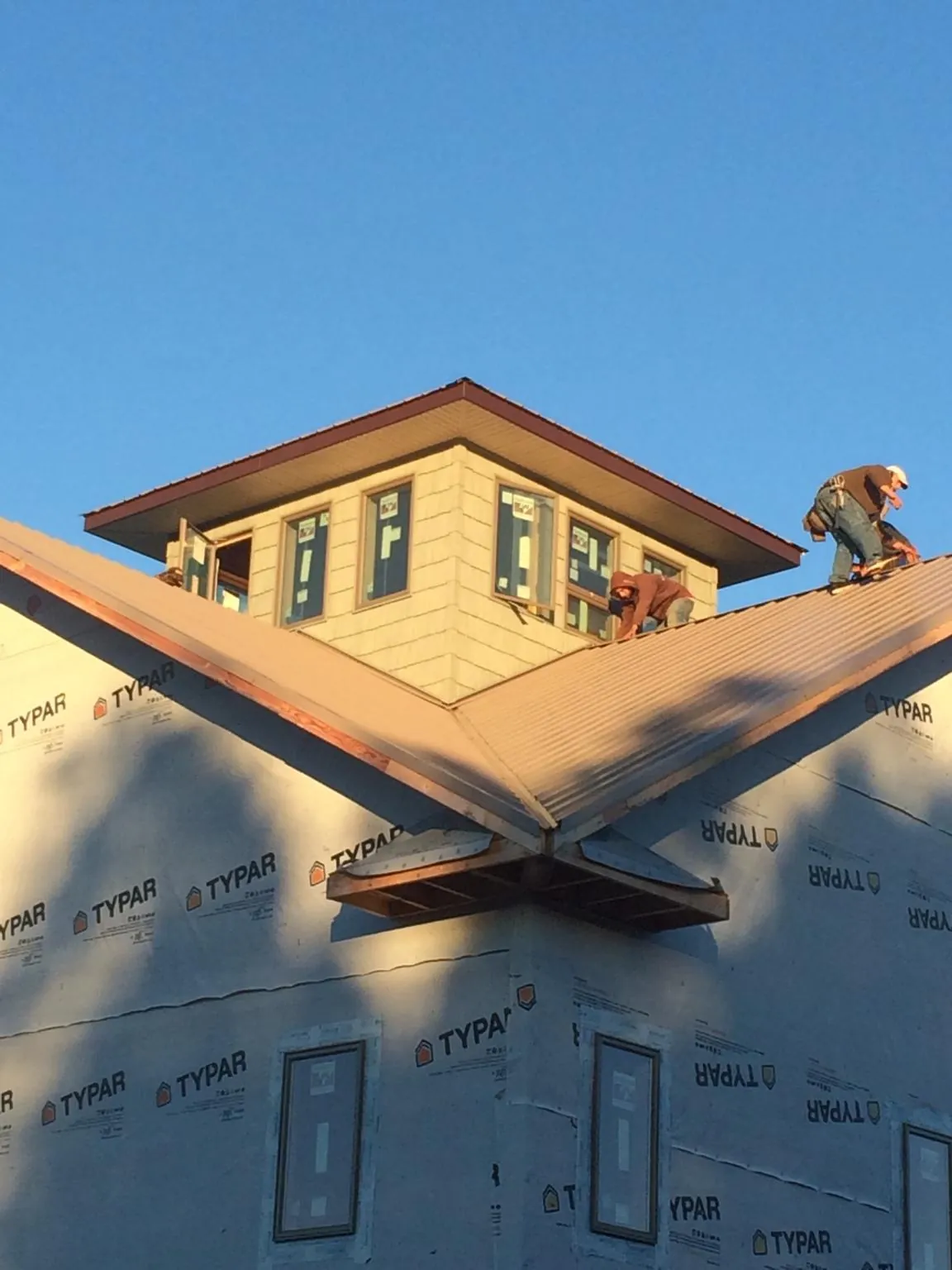 Roofers working around a rooftop cupola on a new metal roof at sunset — Roof Waterproofing in Springvale by Roofing Brothers